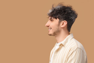 Fototapeta premium Young man with graying hair smiling on beige background