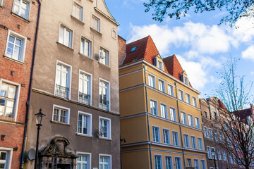 Fototapeta premium A walk near tall buildings with different colors and styles in a lively urban setting during daylight in Gdansk, Poland