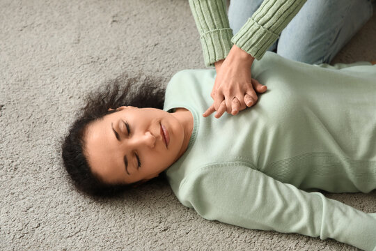 Young woman doing CPR on her unconscious mother having heart attack at home
