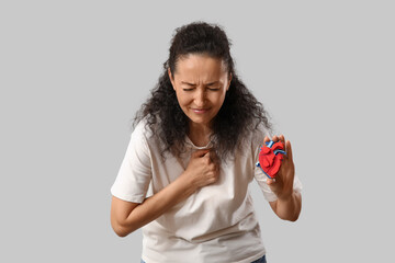 Mature woman with paper organ having heart attack on light background
