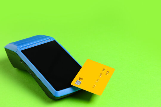 Contactless credit card payment with portable card reader terminal on bright green background, cashless transaction and electronic banking concept