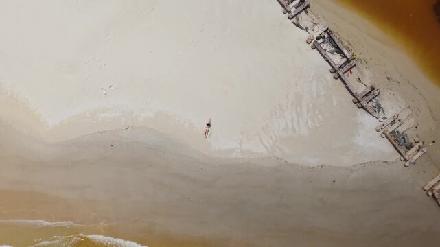 A Caribbean beach portrait of a young Latina girl in a bikini on golden sand aerial view