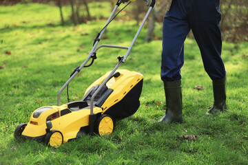 Male gardener using lawn mower outdoors