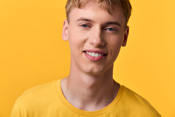 Smiling young man in a tshirt against a bright yellow background, casual lifestyle image...
