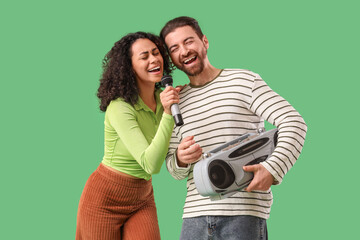 Young couple with microphone and boombox singing on green background © Pixel-Shot