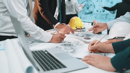 A dynamic team of engineers engaged in a collaborative meeting, reviewing blueprints and discussing innovative project plans using laptops and various construction tools. SACTR - Powered by Adobe