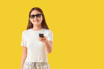 Teenage Asian girl in 3D glasses watching cartoons on yellow background