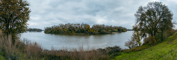 panorama captures the serene Sacramento River winding past banks lined with autumn trees