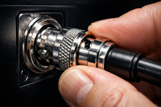 Detailed view of BNC connector being plugged into SDI port of digital cinema camera.