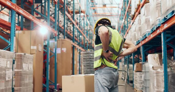 Back pain, logistics and trolley with man in warehouse for delivery, distribution or shipping. Behind, strain and supply chain with injured person in storage depot for inventory or stock management