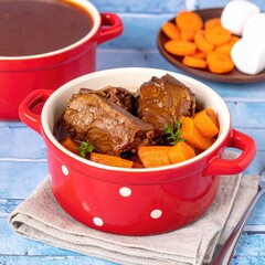 Hearty stew in a red speckled pot, served with carrots