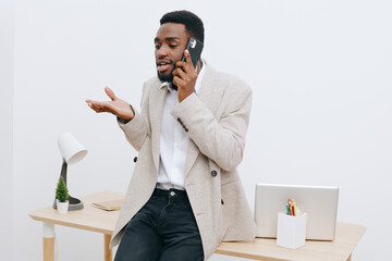 Confident young African American man wearing smart casual outfit talking on mobile phone in modern...