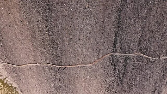 Drone shot of two persons walking on a steep mountain path in 4k filmed from above in 4k