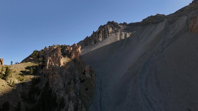 Drone flying backwards with the camera tilting downwards filming mountains and pinnacles in 4k