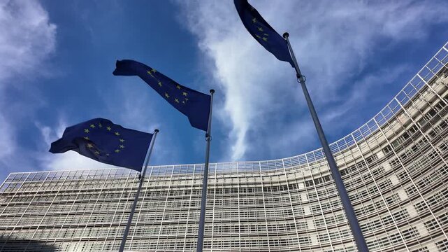Slow motion European Union flags in front of modern buildings in Brussels.