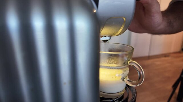 Slow motion coffee flowing from machine into a ceramic cup.