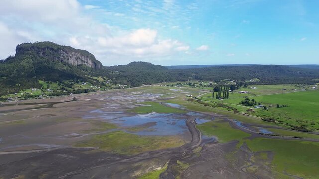 Hualaihue, Chile: Aerial view of coastal area Hualaihue, commune in Lake district near Hornopiren in the green patagonia of Chile with mountain in the background on sunny day. Taken with forward motio