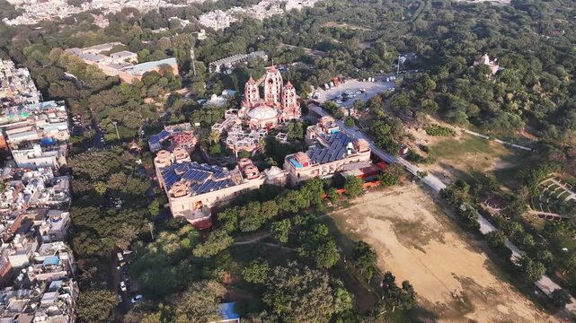 The New Delhi ISKCON Temple stands prominently in the midground, with its distinctive red-and-beige shikharas rising above the surrounding neighborhoods with visible rooftop solar panel array