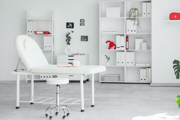 Fototapeta premium Interior of gynecologist's office with couch, shelf units and plants