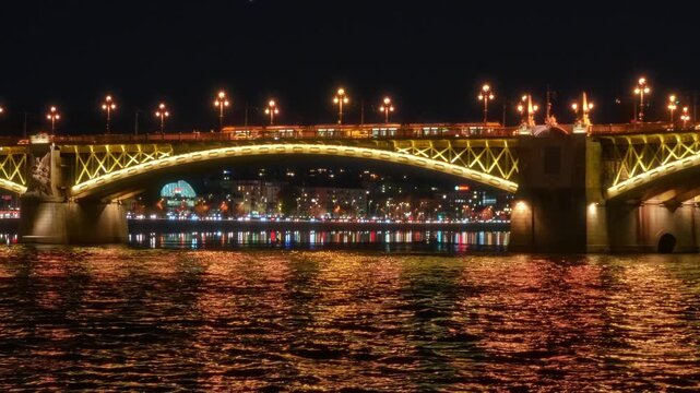 Panoramic view of Budapest city and Danube River at night, bridges, tour boats, urban architecture with beautiful illumination, street lights and road traffic
