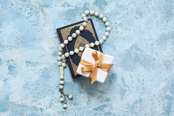 Tasbih, Koran and gift box on blue grunge background. Ramadan celebration