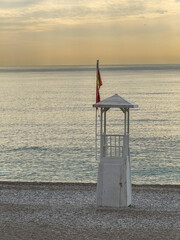 Quiet Konyaalti beach with lifeguard tower under dramatic sunset sky