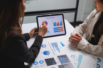 Businesswomen analyzing financial data, discussing market reports