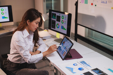 Woman analyzing business data using digital tablet at night