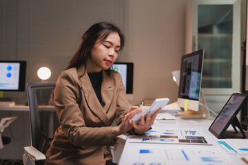 Asian businesswoman analyzing financial data using calculator in office