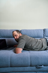 Man lying on couch using laptop