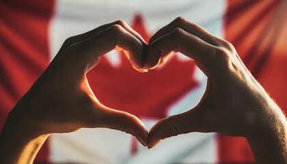 Hands form a heart in front of the Canadian flag. Symbol of pride in the Canadian homeland