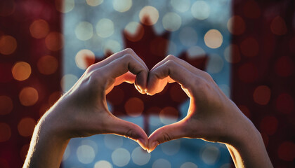 Hands form a heart in front of the Canadian flag. Symbol of pride in the Canadian homeland