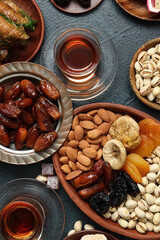 Composition with tasty Eastern sweets and cups of tea for Ramadan on dark color background