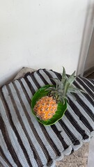 Fresh Small Pineapple on Green Leaf Plate and Striped Mat