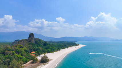 Aerial view of a long white sand beach and turquoise water meeting a lush green coastline with mountains