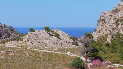 Drone footage captures cars returning from Achata Beach in Karpathos, revealing the wild and rugged landscape surrounding the area.