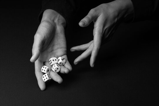 Male hands with white game dices on dark background