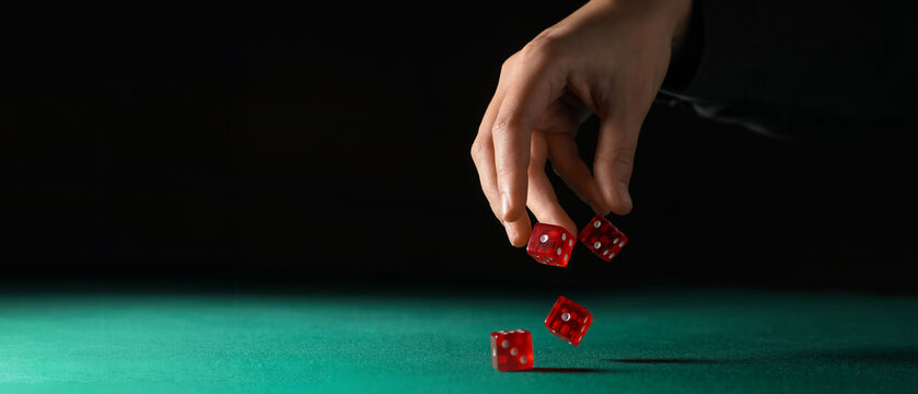 Hand throwing game dices on green background with space for text