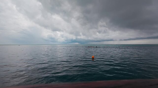rowers in an outrigger canoe paddle across a lagoon on a stormy day