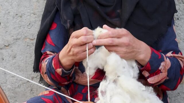 In Kabul, a woman is producing cotton thread yarn through artisanal techniques for carpets and rugs, Qaleen, Afghanistan.
