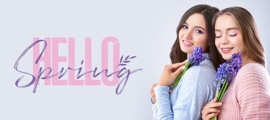 Beautiful young women with hyacinth flowers and text HELLO, SPRING on light background © Pixel-Shot