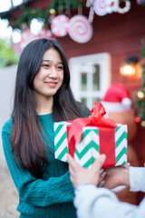 During Christmas time, a happy young woman enjoys a large Christmas gift.