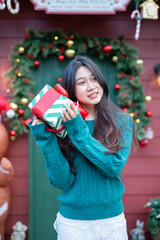  During Christmas time, a happy young woman enjoys a large Christmas gift.
