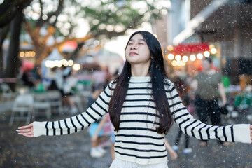  A young woman wearing a scarf and gloves is smiling outdoors in the snow during the winter.