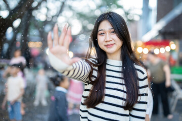 Fototapeta premium A young woman wearing a scarf and gloves is smiling outdoors in the snow during the winter.