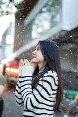  A young woman wearing a scarf and gloves is smiling outdoors in the snow during the winter.
