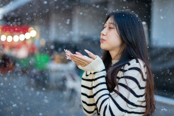  A young woman wearing a scarf and gloves is smiling outdoors in the snow during the winter.