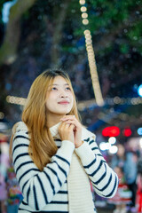  A young woman wearing a scarf and gloves is smiling outdoors in the snow during the winter.