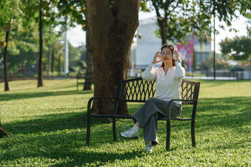 Fototapeta premium Young woman enjoying music with headphones in park