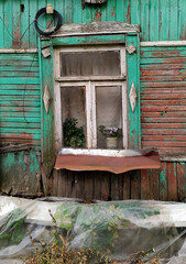 Window in an old wooden house with a flowerpot on it.